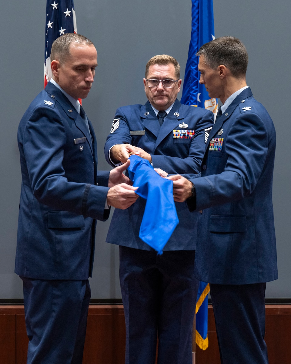 Col. David Sawyer (left), deputy commander of the 655th Intelligence, Surveillance and Reconnaissance Wing based at Wright-Patterson Air Force Base, Ohio, and Col. Jared Broddrick (right) 71st Surveillance Squadron commander, remove the casing from the unit guidon during the activation of ceremony at the Air Force Technical Applications Center, Patrick Space Force Base, Fla., Aug. 1, 2025.  The 71st SURS became the first Reserve squadron attached to AFTAC since the long range detection mission’s inception in 1947.  Also pictured is Master Sgt. Joshua D. Hauser, 71st SURS First Sergeant and guidon bearer for the ceremony.  (U.S. Air Force photo by Matthew S. Jurgens)