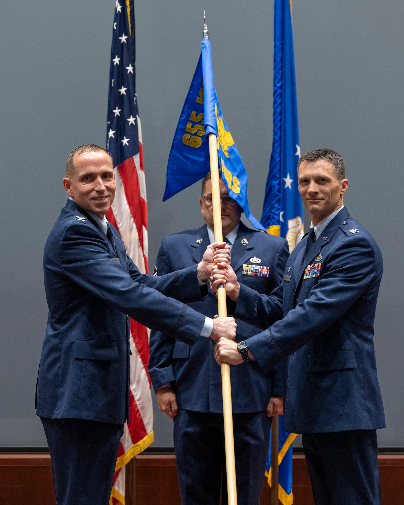 Col. David Sawyer (left), deputy commander of the 655th Intelligence, Surveillance and Reconnaissance Wing based at Wright-Patterson Air Force Base, Ohio, passes the newly unfurled unit guidon to Col. Jared Broddrick (right) 71st Surveillance Squadron commander, during the activation ceremony welcoming the 71st SURS to the Air Force Technical Applications Center Aug. 1, 2025.  The 71st SURS became the first Reserve squadron attached to AFTAC since the long range detection mission’s inception in 1947.  Also pictured is Master Sgt. Joshua D. Hauser, 71st SURS First Sergeant and guidon bearer for the ceremony.    (U.S. Air Force photo by Matthew S. Jurgens)