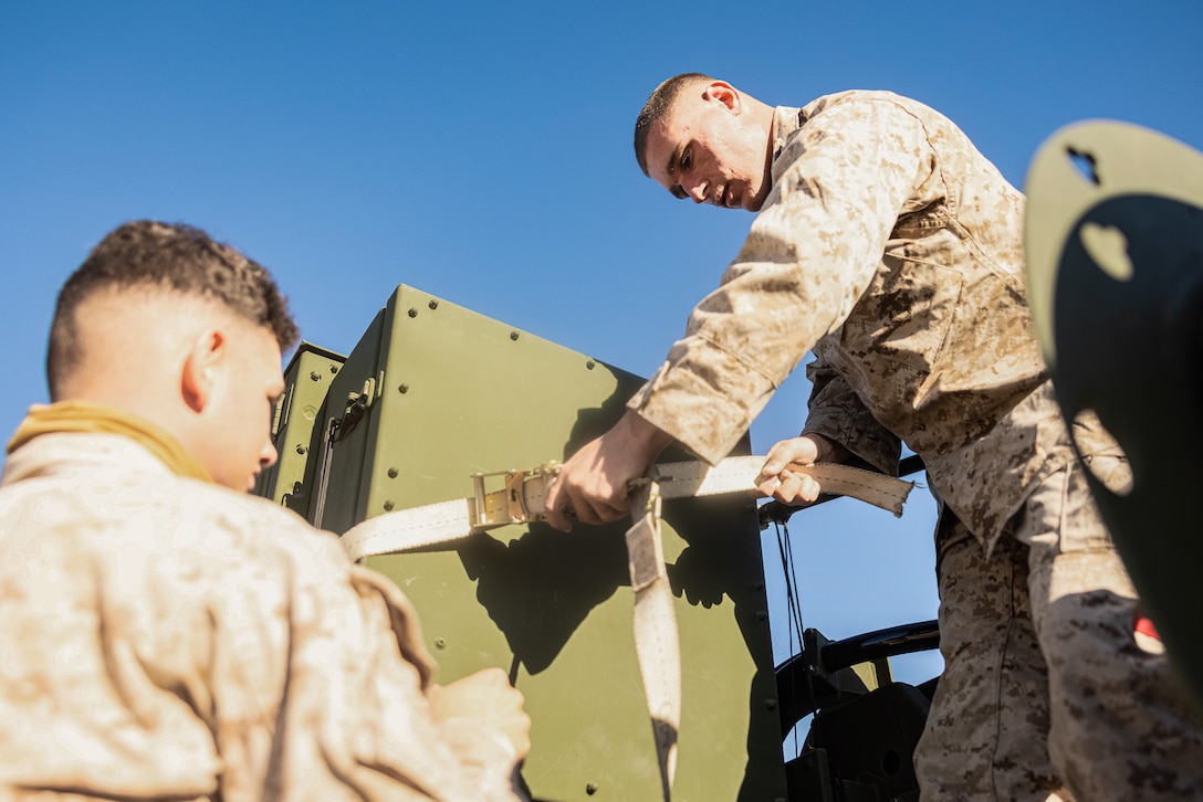 U.S. Marine Corps Lance Cpl. Jayden Kelly, left, and Lance Cpl. Brandon Sardello, both logistics specialists with Combat Logistics Battalion 8, Combat Logistics Regiment 2, 2nd Marine Logistics Group, secures a Medium Range Air Defense Radar for a helicopter support team operation with Marine Heavy Helicopter Squadron (HMH) 361, Marine Aircraft Group 16, 3rd Marine Air Wing, for the first evaluation of the the air transportability of the MRADR during Service Level Training Exercise 4-25 at the Marine Corps Air-Ground Combat Center, Twentynine Palms, California, July 30, 2025. SLTE 4-25 is designed to be a challenging, realistic training environment that produces combat-ready forces capable of operating as an integrated Marine Air Ground Task Force across all domains of military operations. (U.S. Marine Corps photo by Lance Cpl. Judith Ann Lazaro)