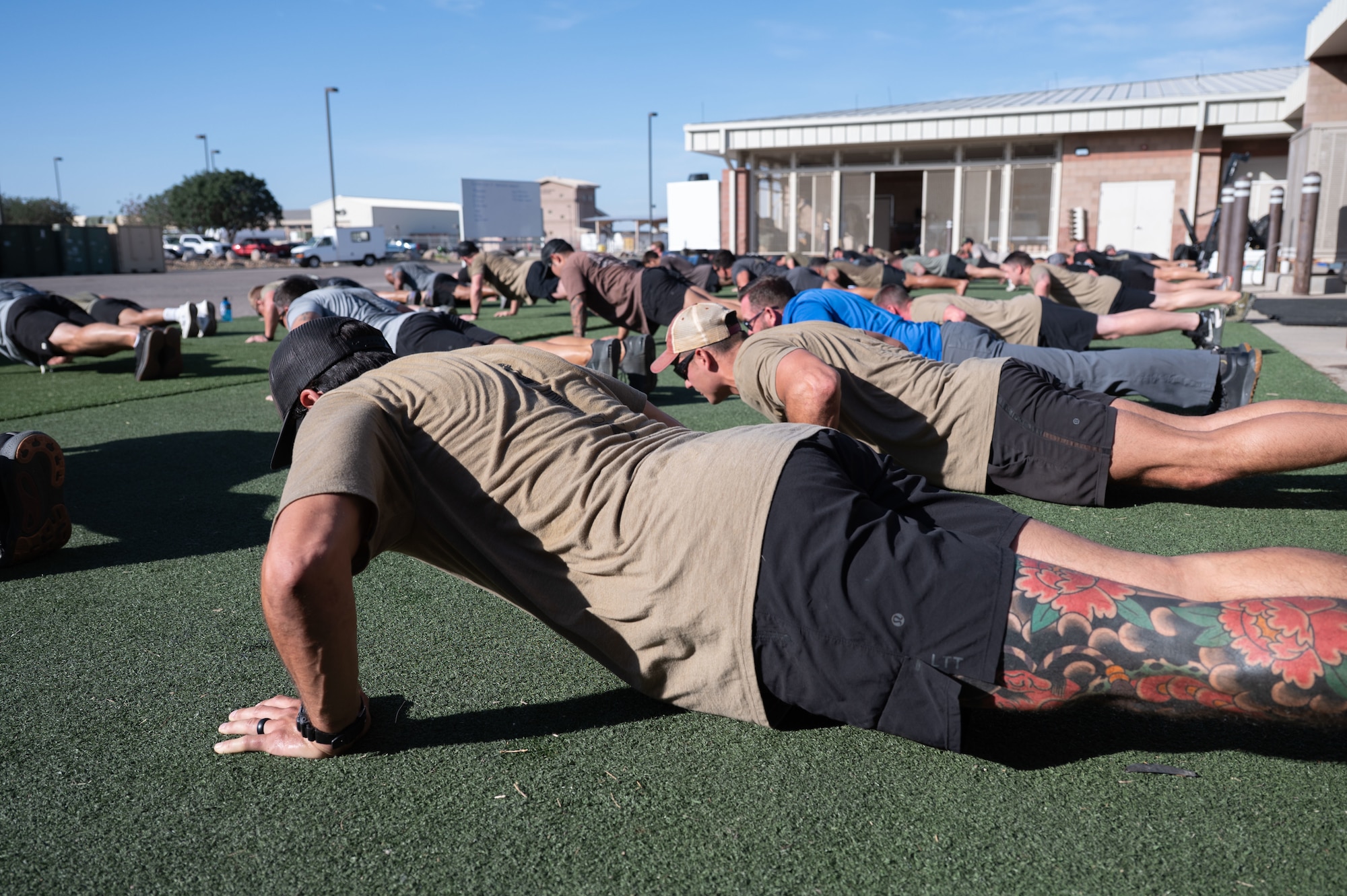 U.S. Airmen from the 48th Rescue Squadron perform memorial push-ups in honor of the fallen airmen in Extortion 17 at Davis-Monthan Air Force Base, August 6, 2025. Ten sets of four-count memorial push-ups were the final exercises that the Airmen performed at the memorial workout. (U.S. Air Force photo by Airman Jaden Kidd)