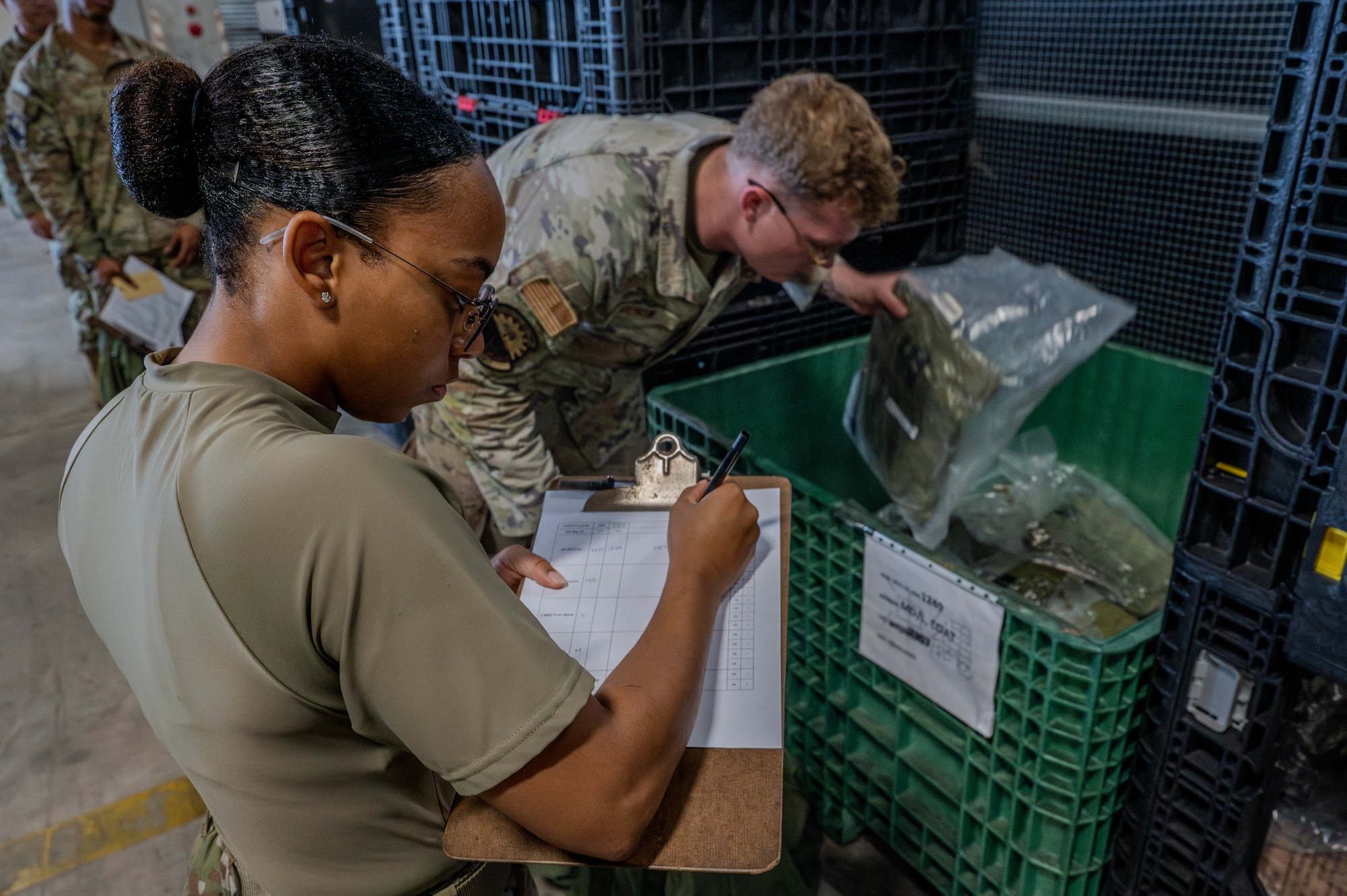Airman checks over other Airman equipping bag.