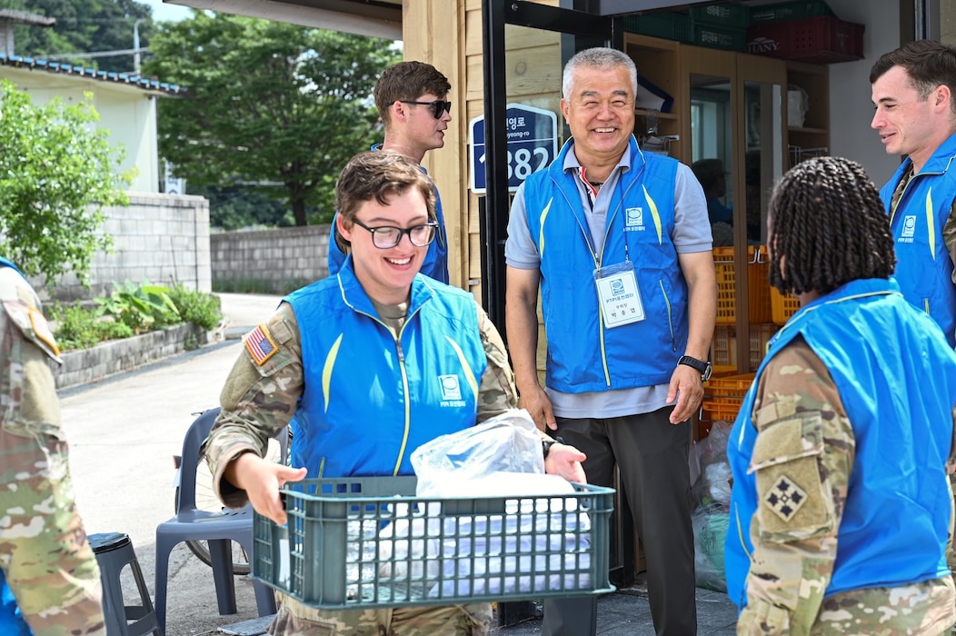 A U.S. Soldier assigned to 2-23 Infantry Battalion, 1st Stryker Brigade Combat Team, 4th Infantry Division, carries supplies alongside People to People International (PTPI) volunteers during a community outreach event in Pocheon, South Korea, Aug. 7, 2025. In collaboration with 210th Field Artillery Brigade, Soldiers and PTPI members teamed up to serve local elders with food and support during the summer senior community event.