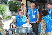 A U.S. Soldier assigned to 2-23 Infantry Battalion, 1st Stryker Brigade Combat Team, 4th Infantry Division, carries supplies alongside People to People International (PTPI) volunteers during a community outreach event in Pocheon, South Korea, Aug. 7, 2025. In collaboration with 210th Field Artillery Brigade, Soldiers and PTPI members teamed up to serve local elders with food and support during the summer senior community event.