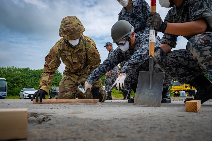 A Japan Air Self Defense Force airmen assigned to the 2nd Air Wing displays concrete smoothing techniques with U.S. Air Force Airman 1st Class Josiah Smith, left, 35th Civil Engineer Squadron firefighter, during exercise Resolute Force Pacific 2025 while conducting Rapid Airfield Damage Repair training at Chitose Air Base, Japan, July 29, 2025.