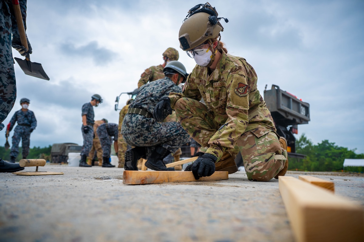 U.S. Air Force Airman 1st Class Reese Wildes, right, 35th Civil Engineer Squadron electrical systems specialist, smooths concrete during exercise Resolute Force Pacific 2025 while conducting Rapid Airfield Damage Repair training at Chitose Air Base, Japan, July 29, 2025.