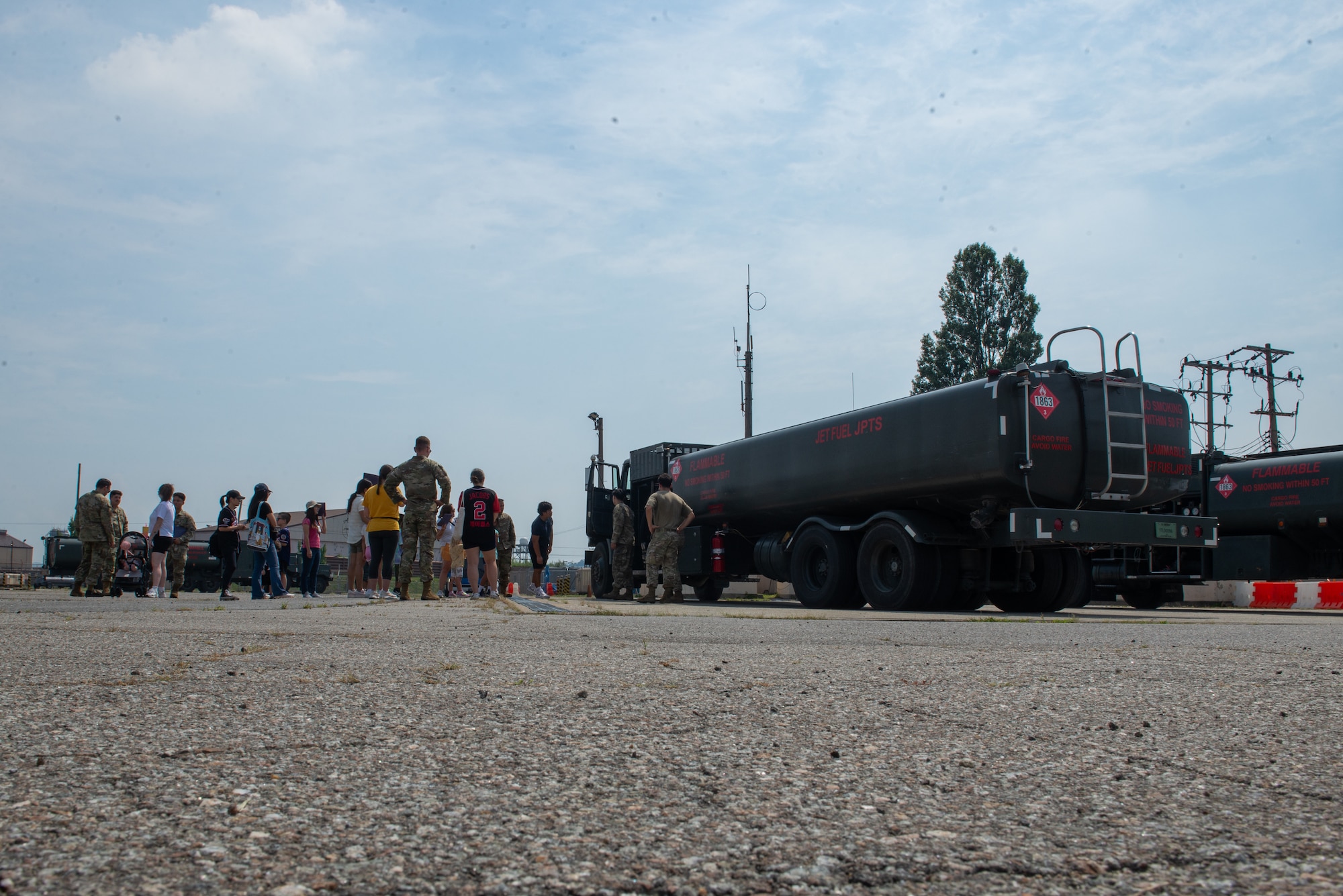 Airmen and families look at a fuel truck.