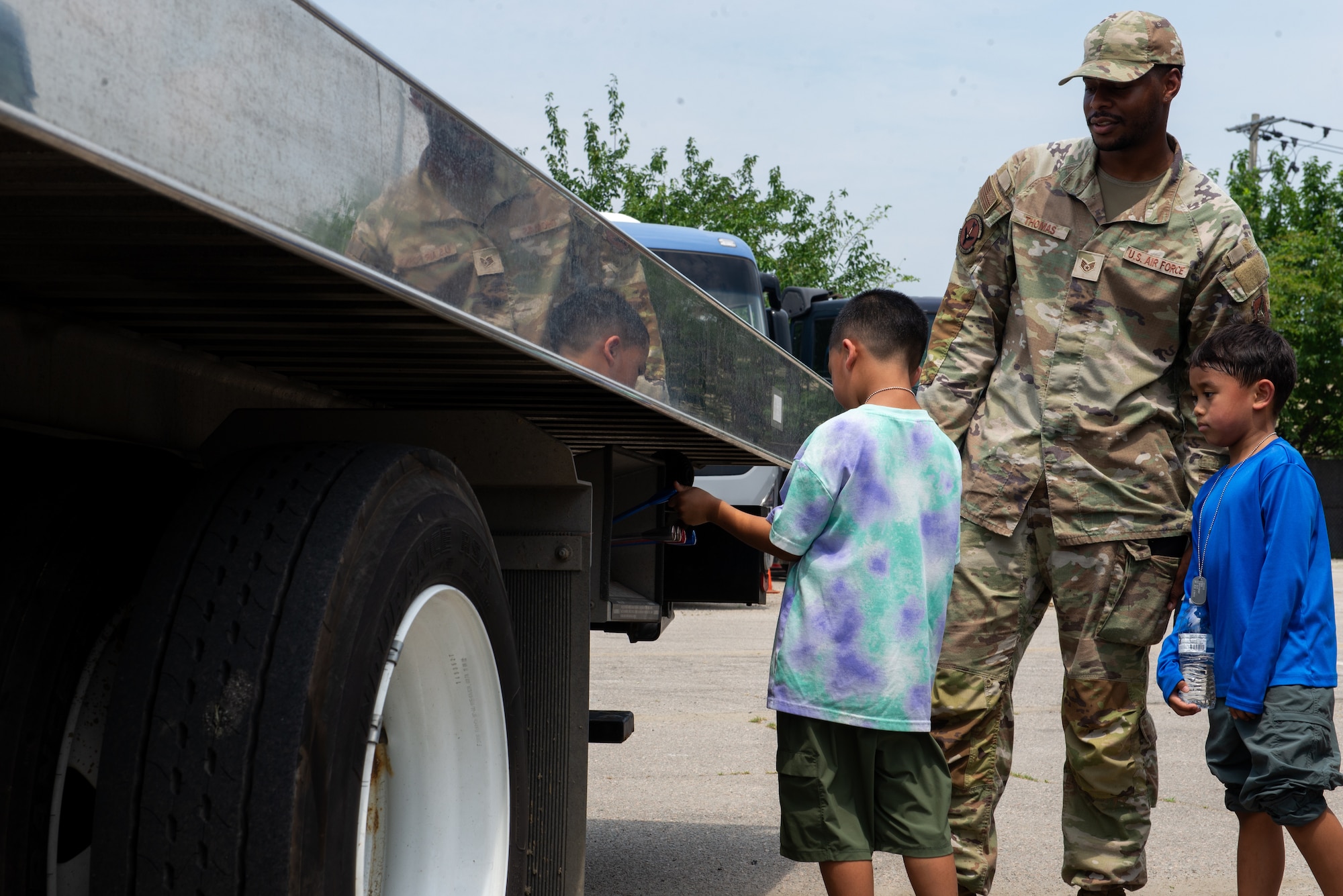 An Airman supervises children control a tow truck bed.