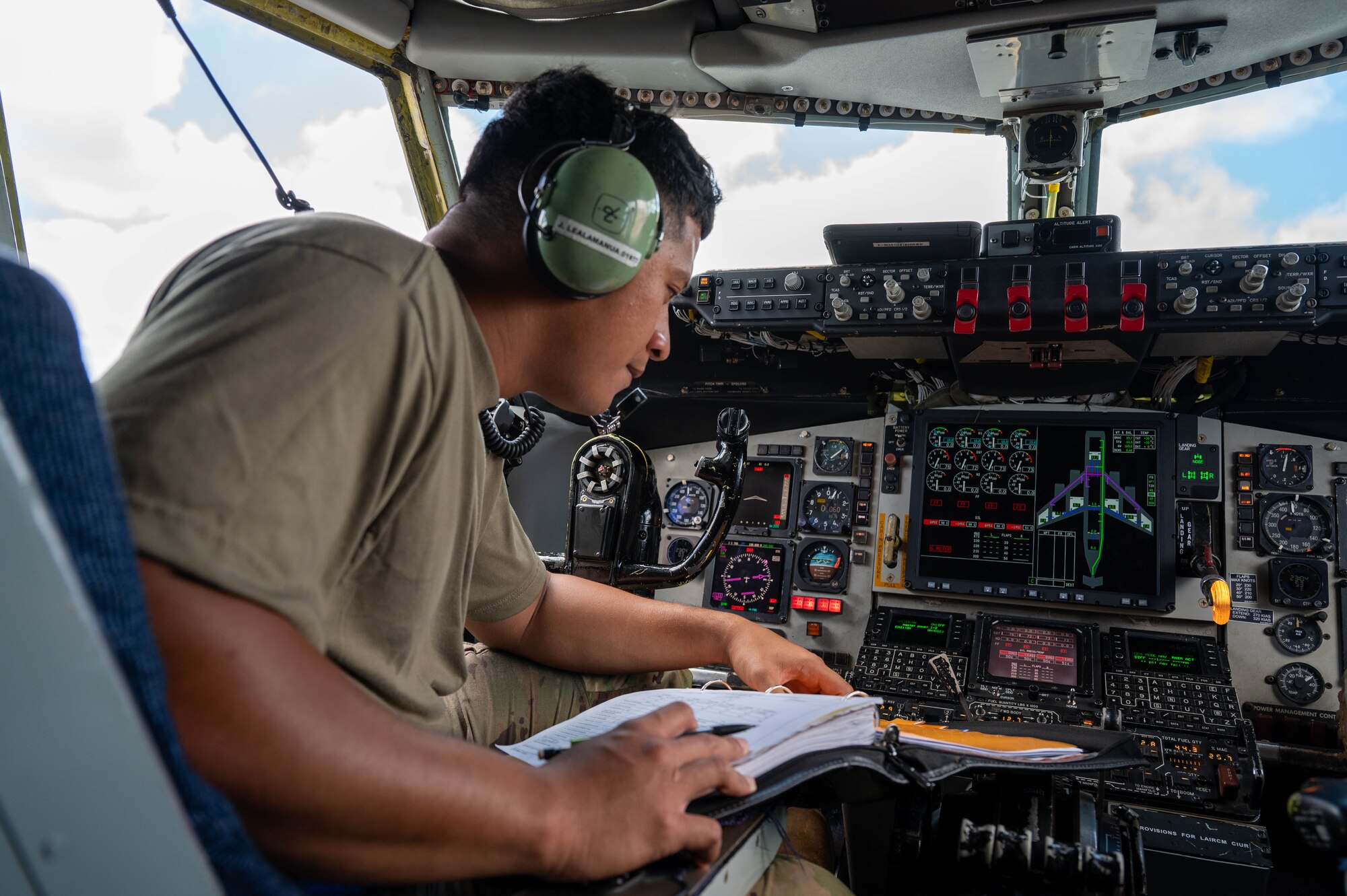 A crew chief leans forward to look at gauges in the the cockpit of a KC-35 Stratotanker