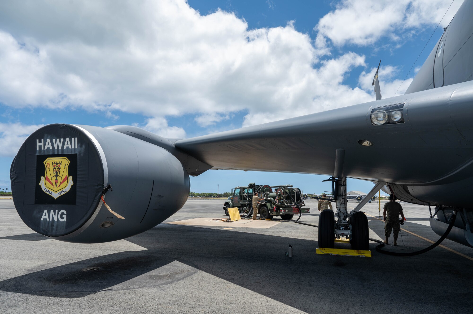 Two Airmen stand beside a KC-35 aircraft on the flightline preparing to fuel it.