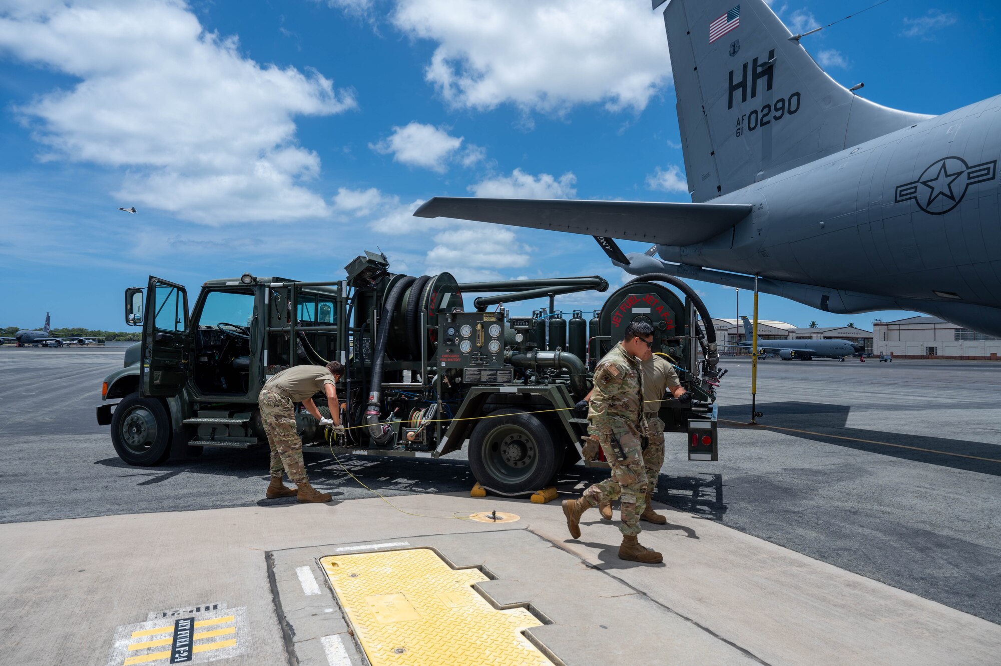 Two Airmen walk toward an aircraft to prepare it for ground refueling.