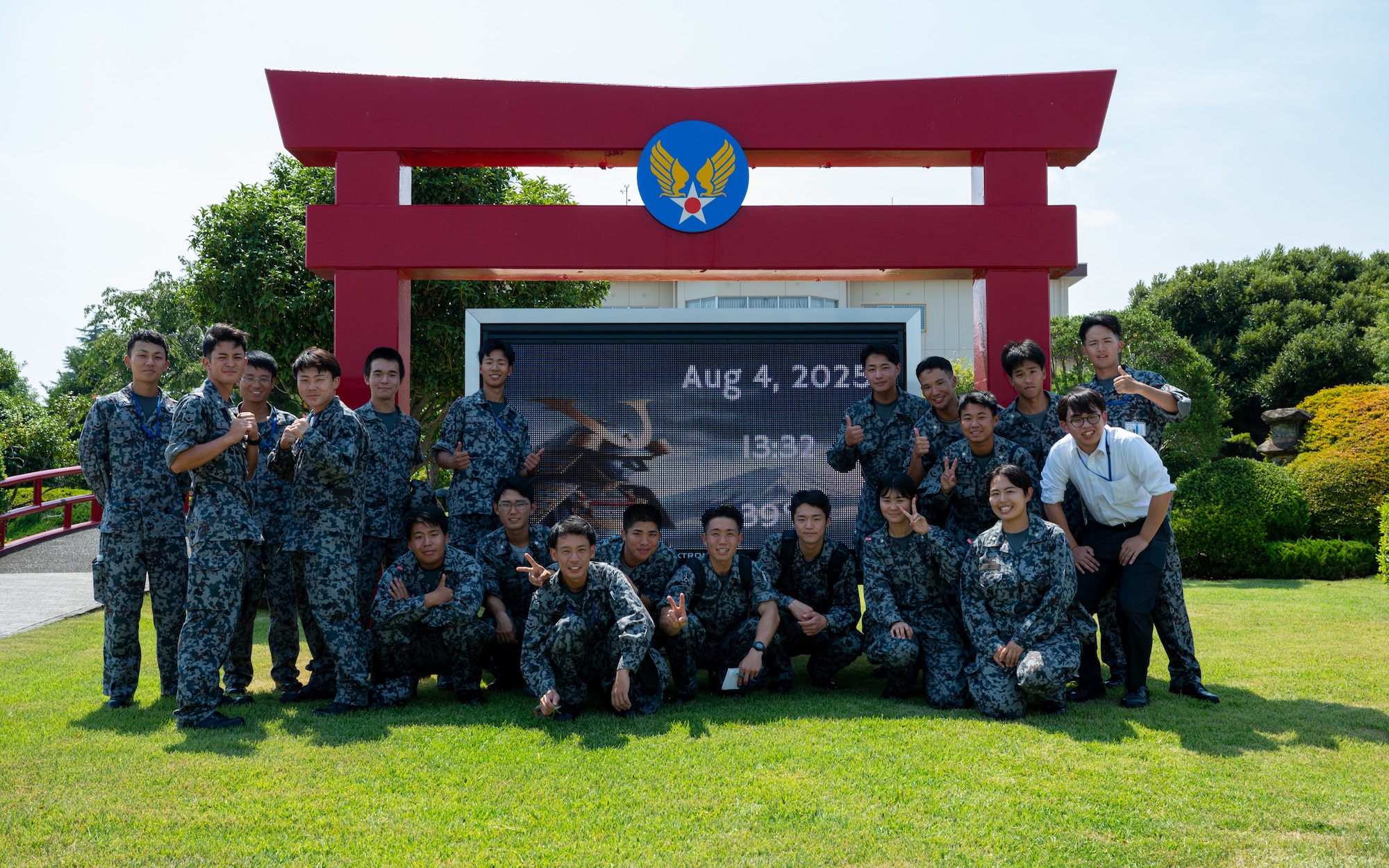 Newly assigned members to the Japan Air Self-Defense Force Operations Support Wing and Air Intelligence Wing pose for a photo in front of the distinguished visitor garden marquee at Yokota Air Base, Japan.