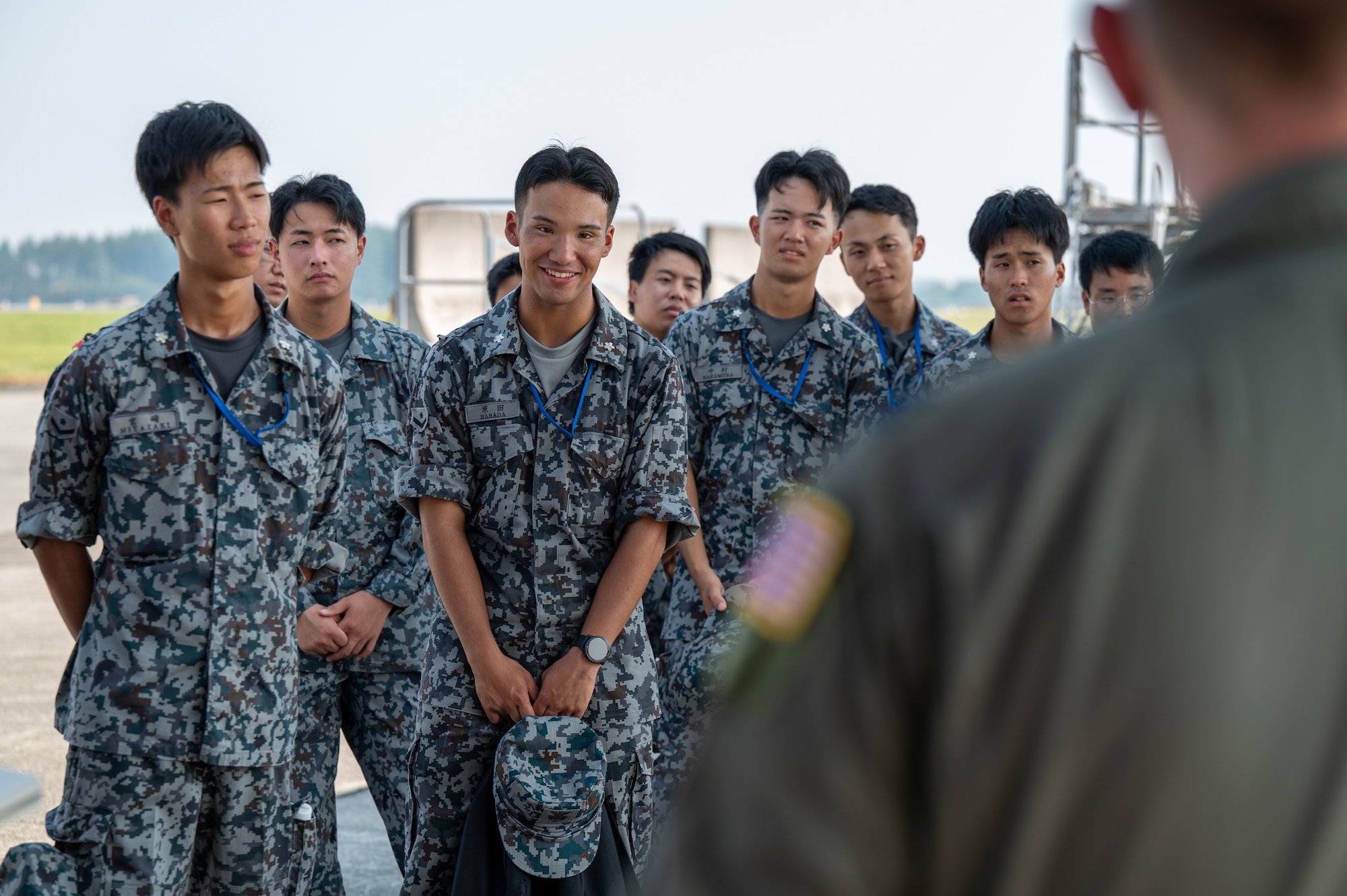 Newly assigned members to the Japan Air Self-Defense Force Operations Support Wing and Air Intelligence Wing listen to U.S. Air Force Capt. William Waller, 36th Airlift Squadron C-130J Super Hercules pilot, during a static display tour of a C-130J at Yokota Air Base, Japan.