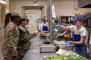 U.S. Air Force Staff Sgt. Afua Kwenua Dwiredu Gyamera, left, 18th Operational Medical Readiness Squadron non-commissioned officer in charge of community health, and U.S. Air Force Senior Airman Reina Morales, 18th OMRS public health technician, check the temperature of the food at Marshall Dining Facility on Kadena Air Base, Japan, Aug. 4, 2025.