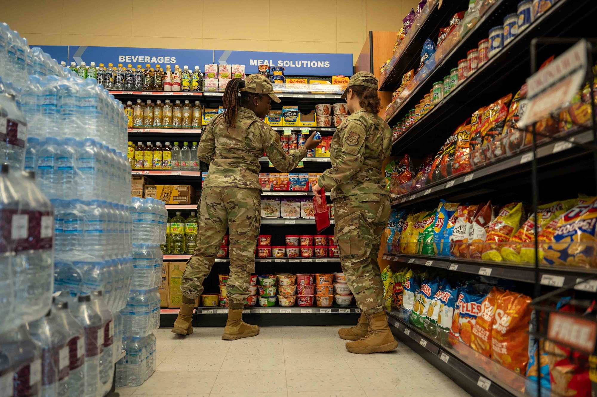 U.S. Air Force Staff Sgt. Afua Kwenua Dwiredu Gyamera, left, 18th Operational Medical Readiness Squadron non-commissioned officer in charge of community health, and U.S. Air Force Senior Airman Reina Morales, 18th OMRS public health technician, check for the expiration date on food items at Kadena Air Base, Japan, Aug. 6, 2025.