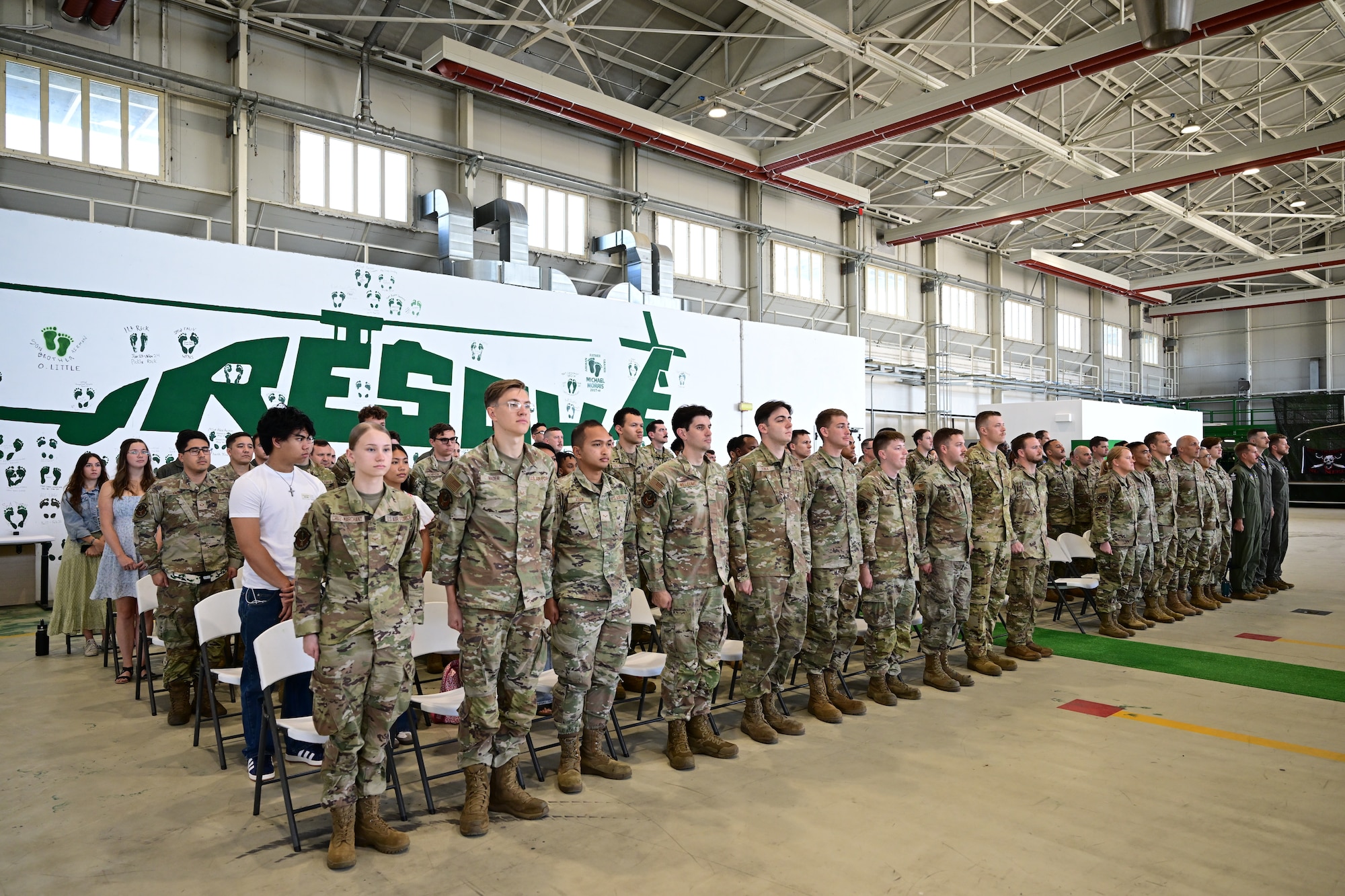 Service members, family and friends stand during a ceremony.