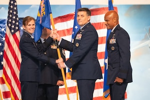 Two people standing passing a flag