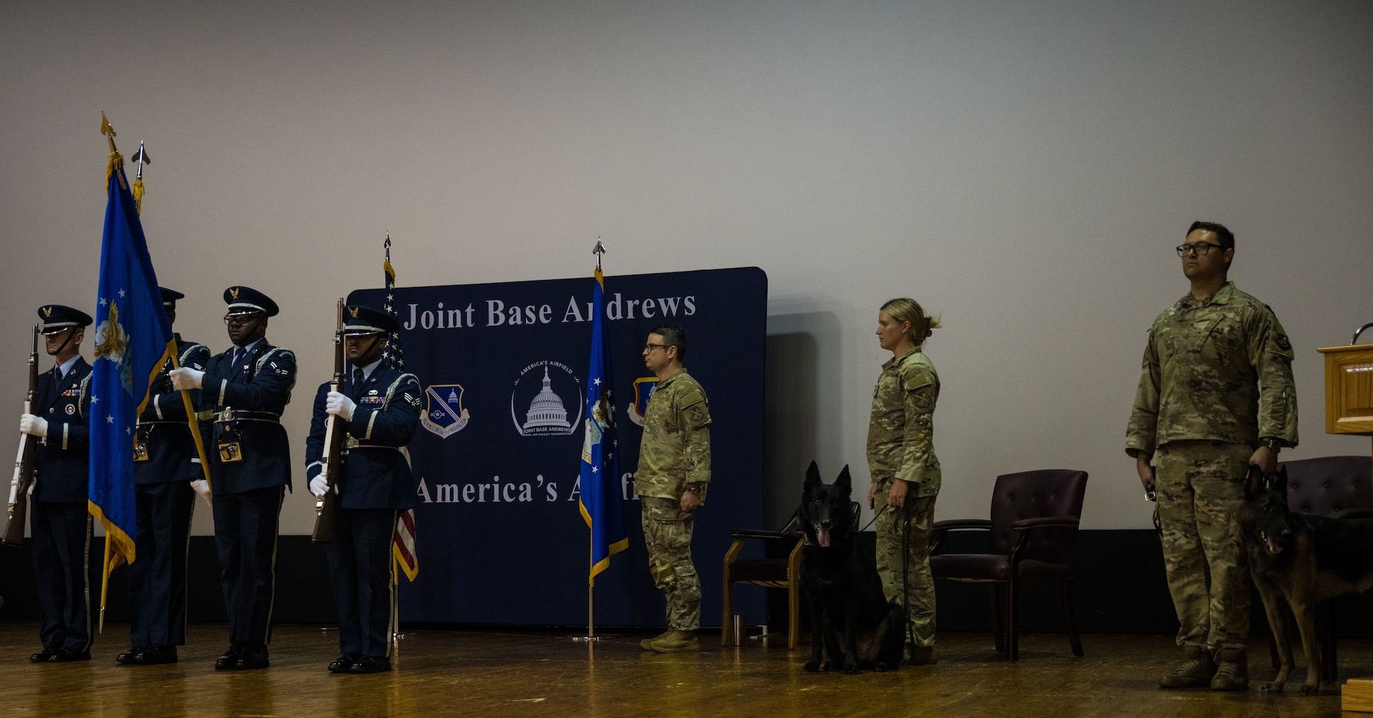 U.S. Air Force Honor Guard members, 316th Security Support Squadron personnel, and Military Working Dogs Cchango and Nero stand on stage for the presentation of the colors during a retirement ceremony at Joint Base Andrews, Md., Aug. 6, 2025.