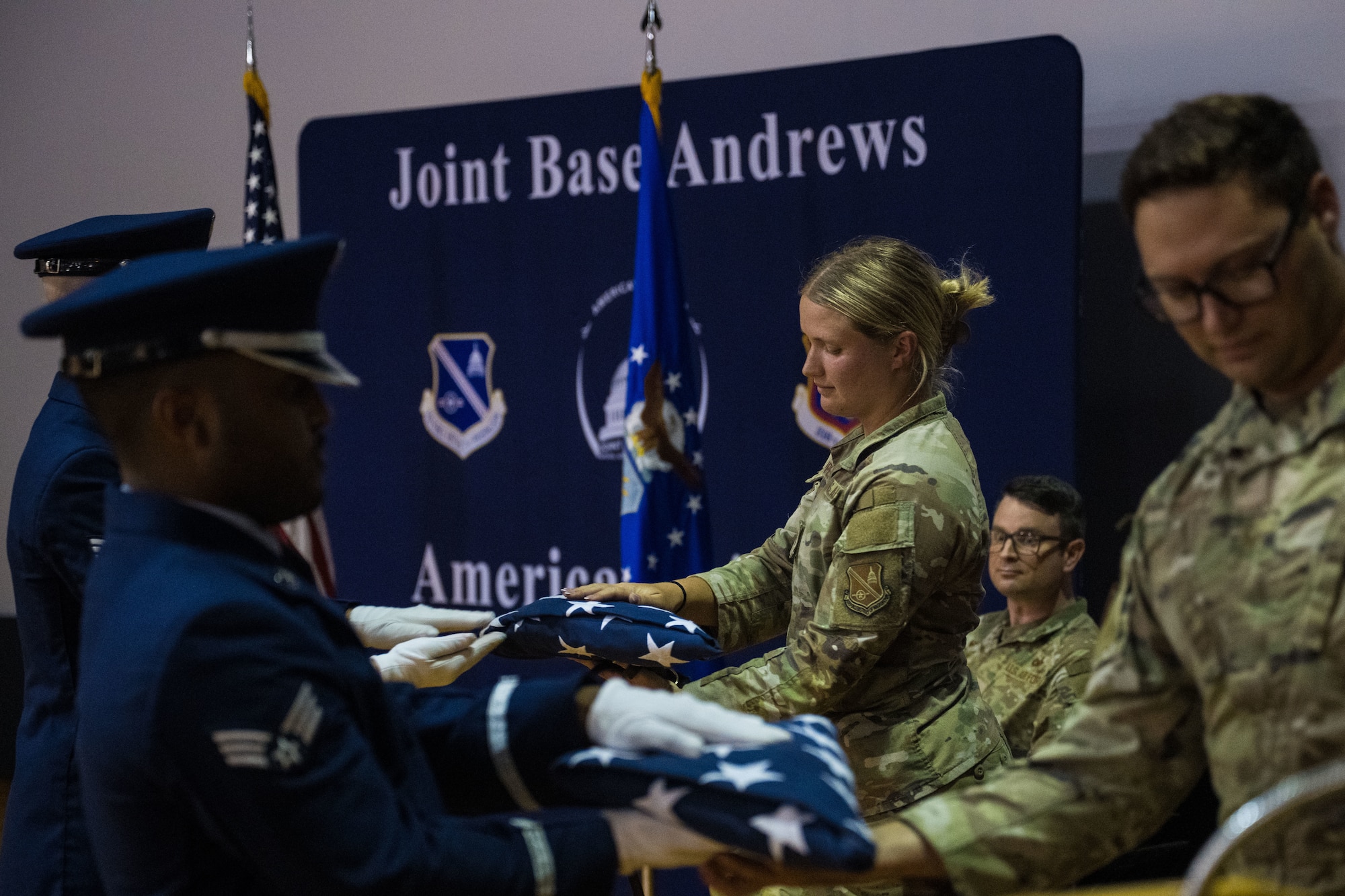 U.S. Air Force Staff Sgts. Alexis Krippel and Zachary Scott, military working dog handlers with the 316th Security Support Squadron, receive folded American flags on behalf of MWDs Chango and Nero during a retirement ceremony at Joint Base Andrews, Md., Aug. 6, 2025.