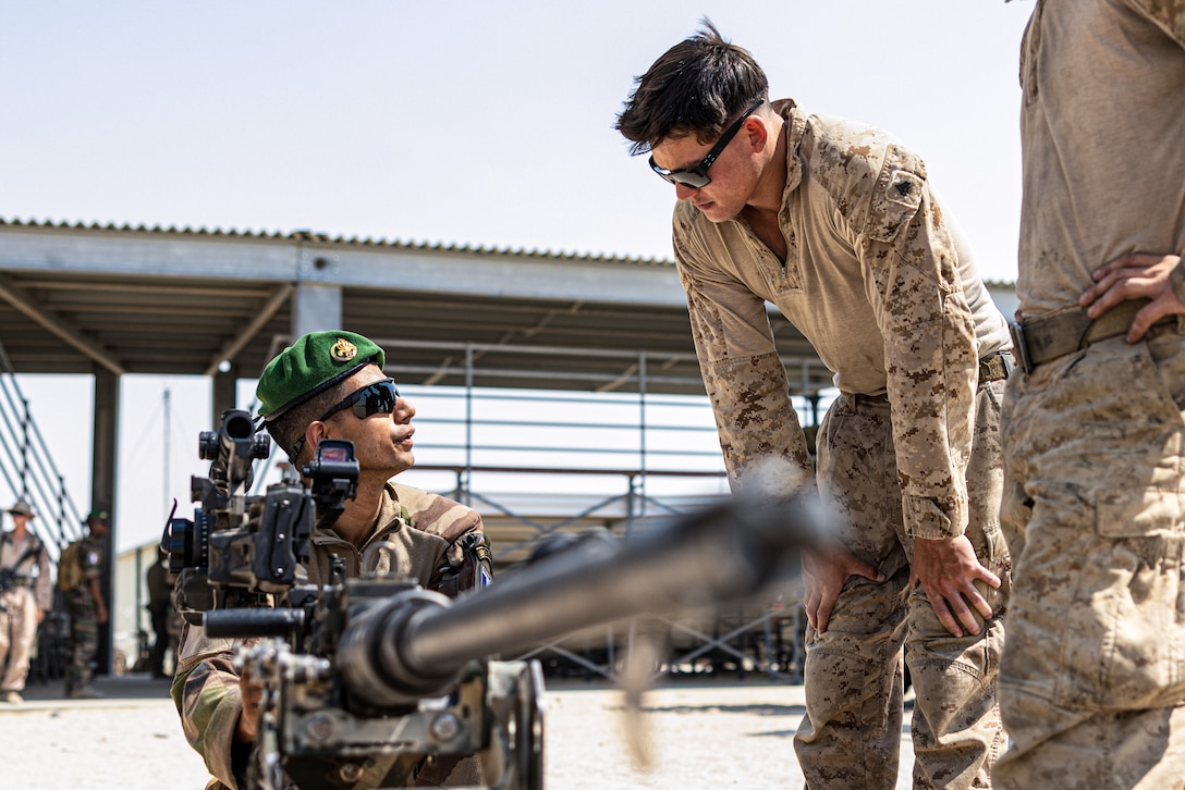 U.S. Marines with Marine Air Ground Task Force-6 and a French soldier with 2nd Foreign Infantry Regiment, 6th Light Armored Brigade Command, discuss weapon systems during Service Level Training Exercise 4-25, on Marine Corps Air-Ground Combat Center, Twentynine Palms, California, Aug. 4, 2025. SLTE 4-25 is designed to be a challenging, realistic training environment that produces combat-ready forces capable of operating as an integrated Marine Air Ground Task Force across all domains of military operations. (U.S. Marine Corps photo by Lance Cpl. Judith Ann Lazaro)