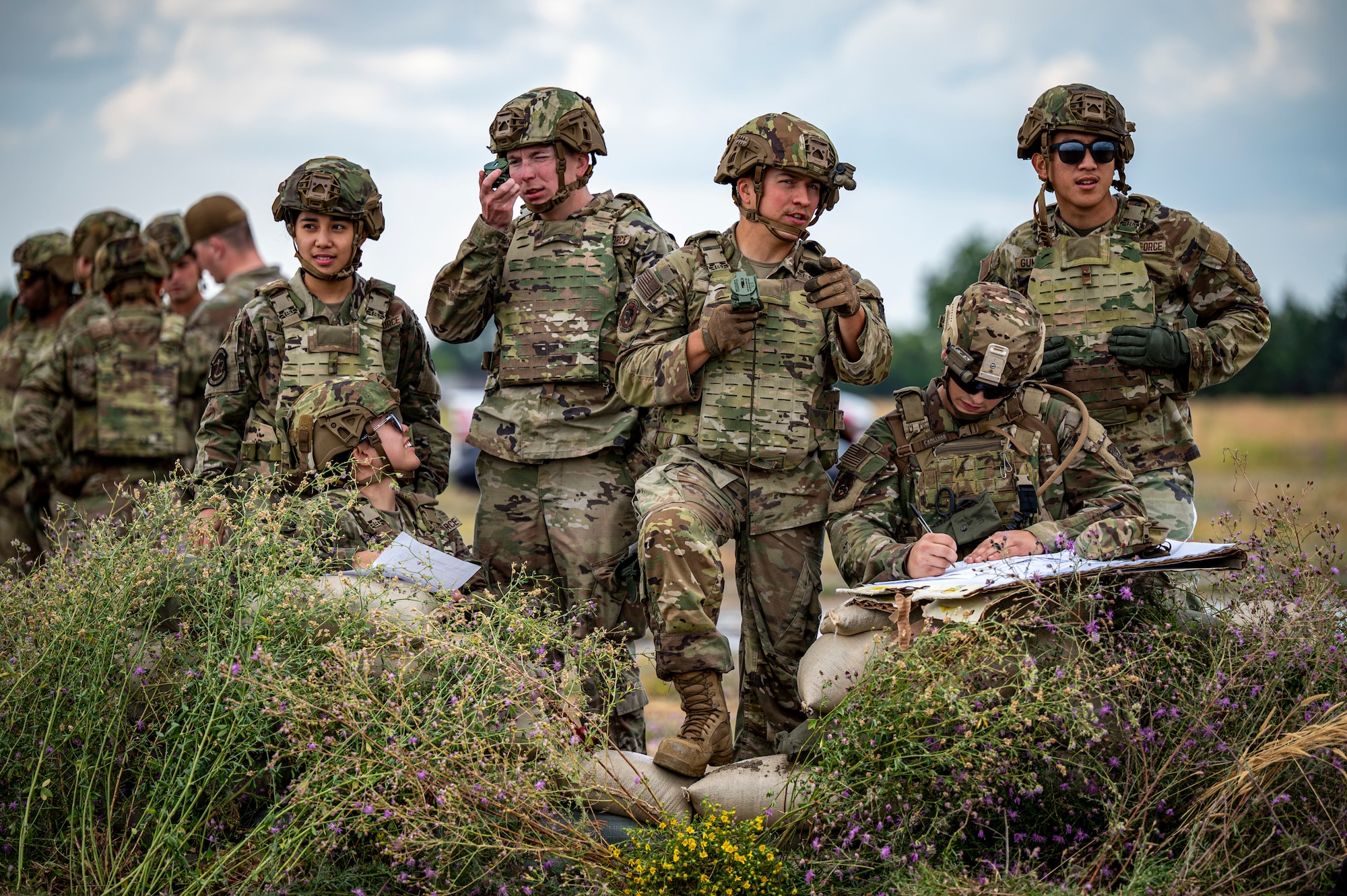 A group of U.S. Airmen stand behind a makeshift barrier.