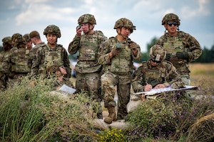 A group of U.S. Airmen stand behind a makeshift barrier.