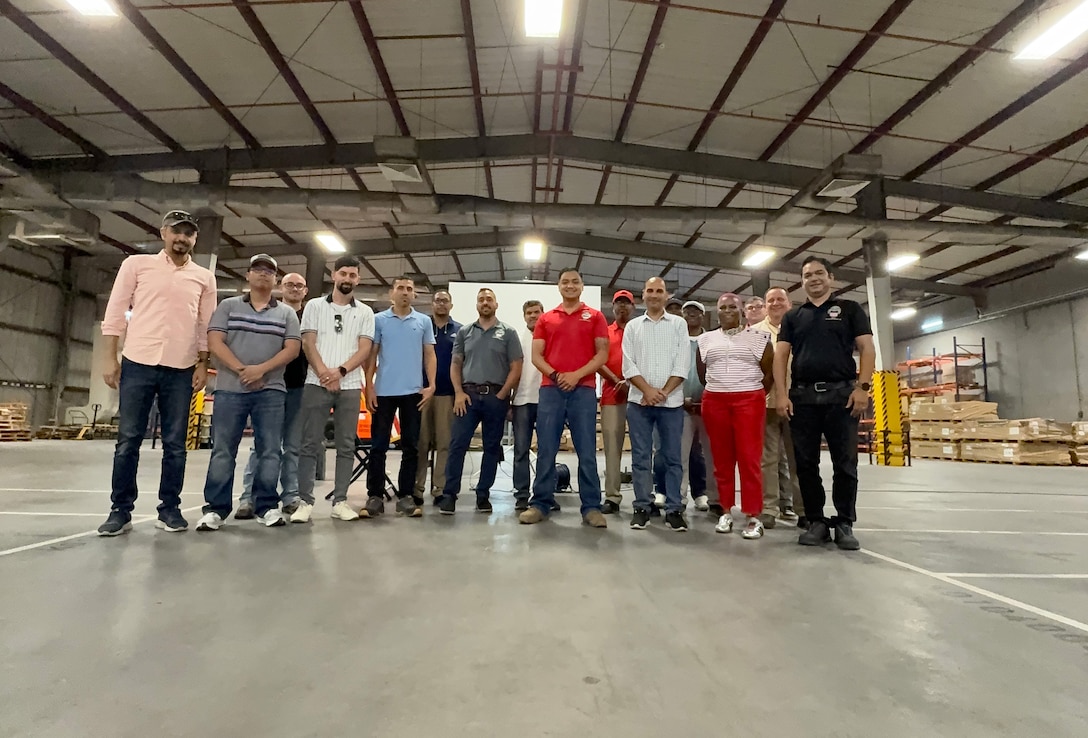 People gathered in a warehouse pose for a photo.