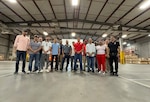 People gathered in a warehouse pose for a photo.