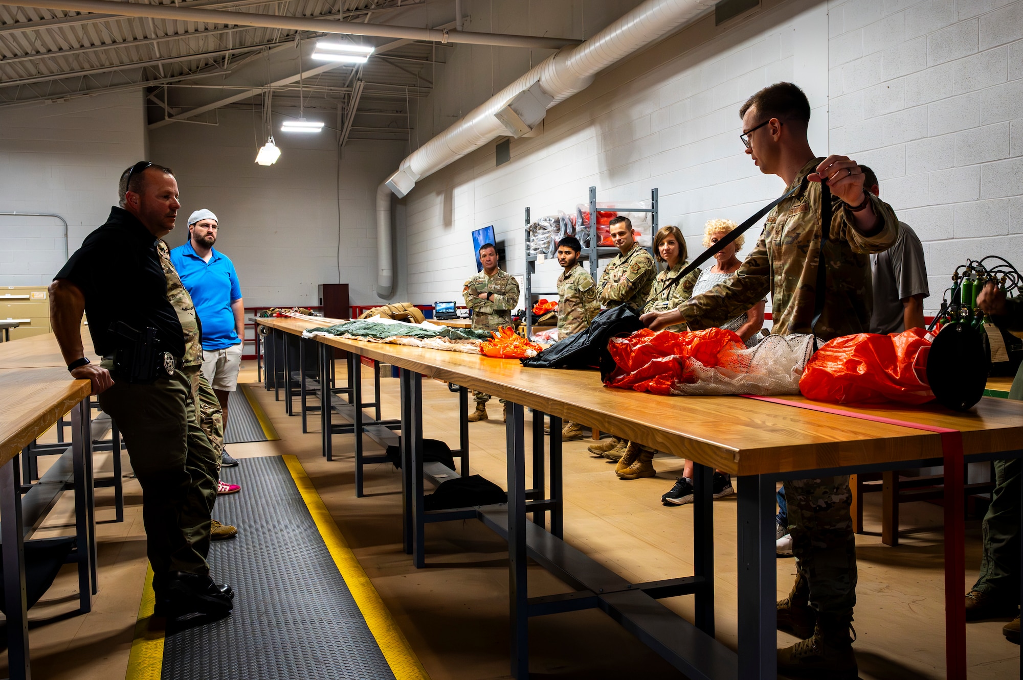 U.S. Air Force Staff Sgt. Benjamin Meadows, 317th Operational Support Squadron aircrew flight equipment craftsman , teaches Dyess and Goodfellow Air Force Base honorary commanders how to pack parachutes during a tour at Dyess Air Force Base, Texas, Aug. 6, 2025. The Dyess Honorary Commander program is an executive-level program intended to educate civic leaders who have limited knowledge of the Air Force and Dyess to foster public support for the base and its Airmen and families. (U.S. Air Force photo by Staff Sgt. Leon Redfern)