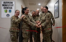 Members of Minot leadership and the Chapel Team cut a ribbon during the opening ceremony for the Airmen Ministry Center at Minot Air Force Base, North Dakota, Aug. 8, 2025. The Airmen Ministry Center is a space designed to foster connection, relaxation and camaraderie among Airmen of all ranks. (U.S. Air Force photo By Airman 1st Class Wesley Davies)