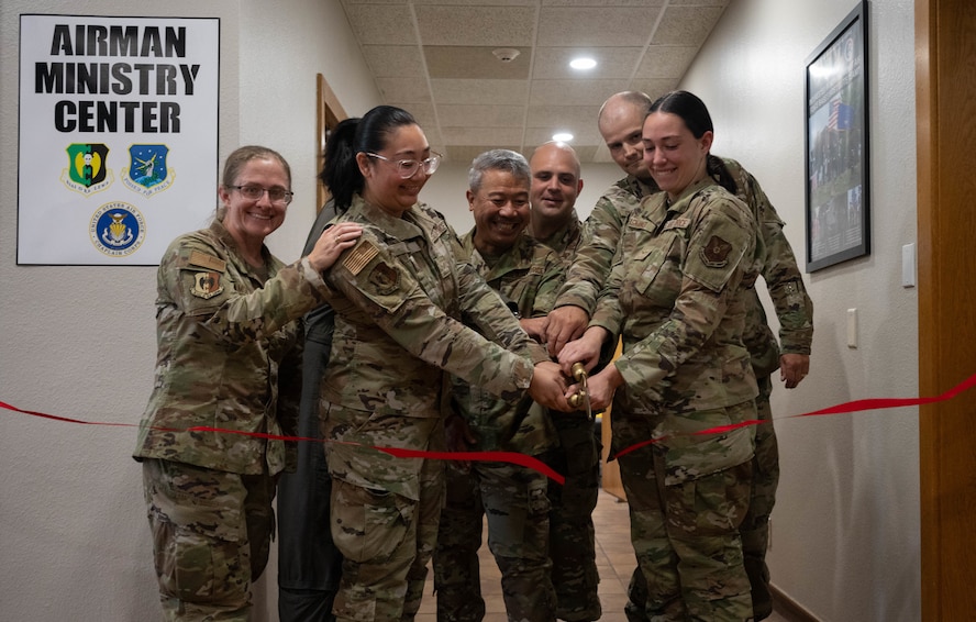 Members of Minot leadership and the Chapel Team cut a ribbon during the opening ceremony for the Airmen Ministry Center at Minot Air Force Base, North Dakota, Aug. 8, 2025. The Airmen Ministry Center is a space designed to foster connection, relaxation and camaraderie among Airmen of all ranks. (U.S. Air Force photo By Airman 1st Class Wesley Davies)