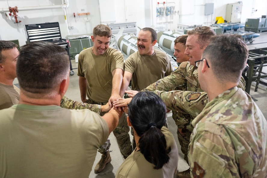 U.S. Air Force Airmen from the 5th Munitions (5MUNS) huddle after completing a training event at Minot Air Force Base, North Dakota, August 4, 2025. 5MUNS is training in preparation for the Air Force Combat Operations Competition, where they will compete against other munitions squadrons in munition building exercises.