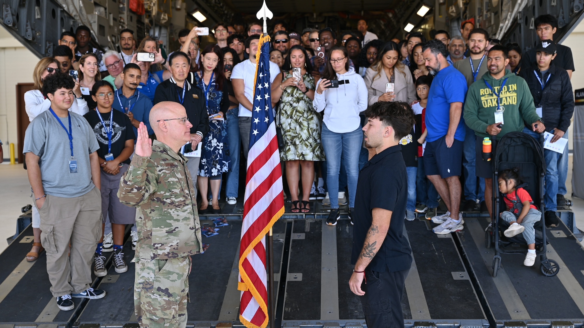 Col. Cade C. Gibson, left, administers the oath of enlistment to new recruit Shaun Ian Rodriguez on the ramp of a C-17 Globemaster III during the Travis Air Reserve Experience at Travis Air Force Base, Calif., Aug. 3, 2025. The ceremony took place in front of event attendees, community leaders, and wing leadership, symbolizing the start of Rodriguez's career as a Reserve Airman. The Travis Air Reserve Experience is a recruiting event designed to give community members an opportunity to interact directly with Reserve Airmen, learn about career paths, and explore the mission of the 349th Air Mobility Wing.