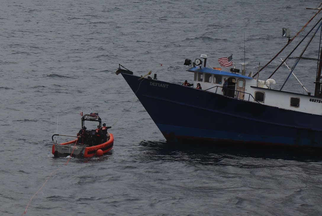 A Coast Guard Cutter Alder small boat crew is seen throwing a heaving line to the fishing vessel Defiant.