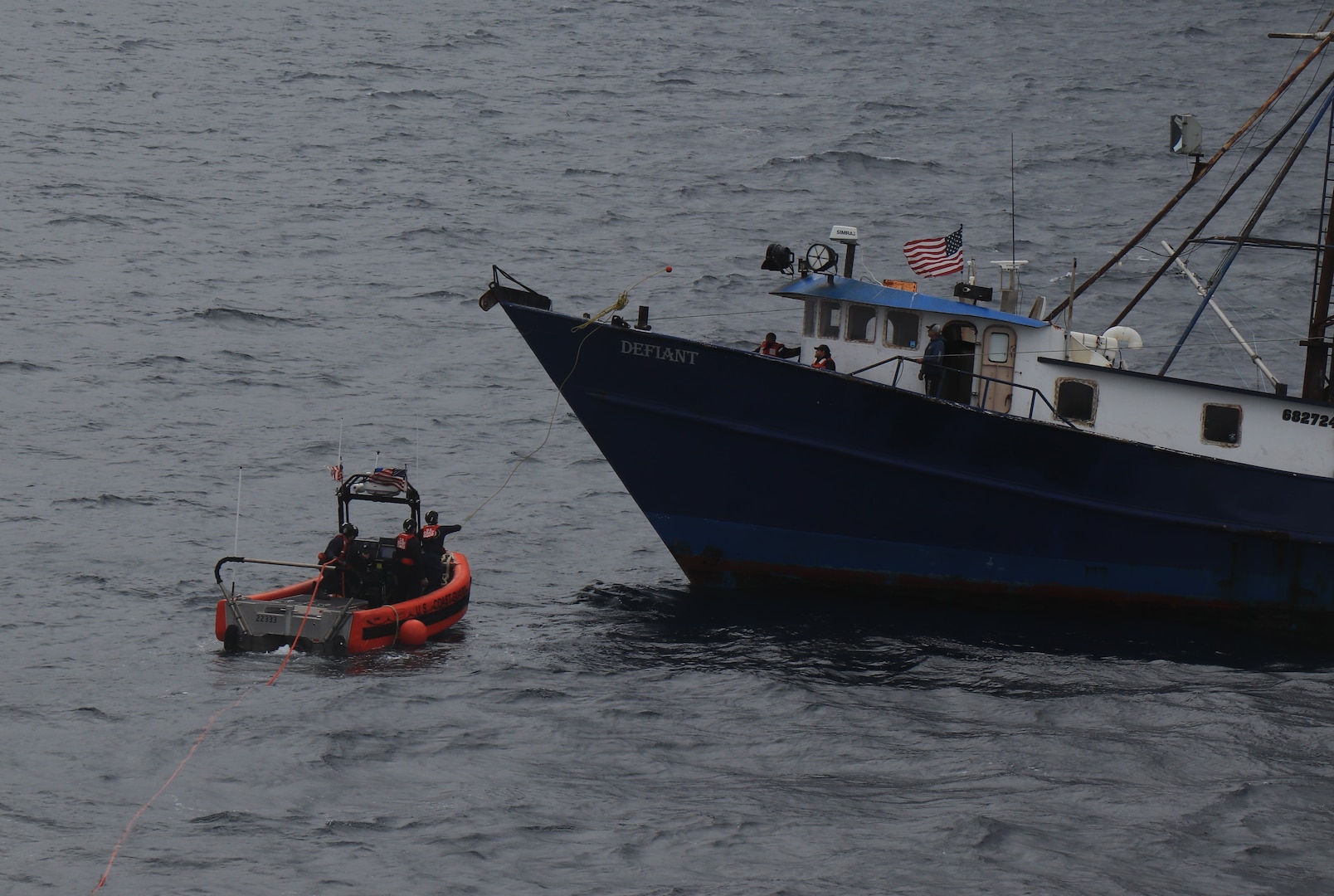 A Coast Guard Cutter Alder small boat crew is seen throwing a heaving line to the fishing vessel Defiant.