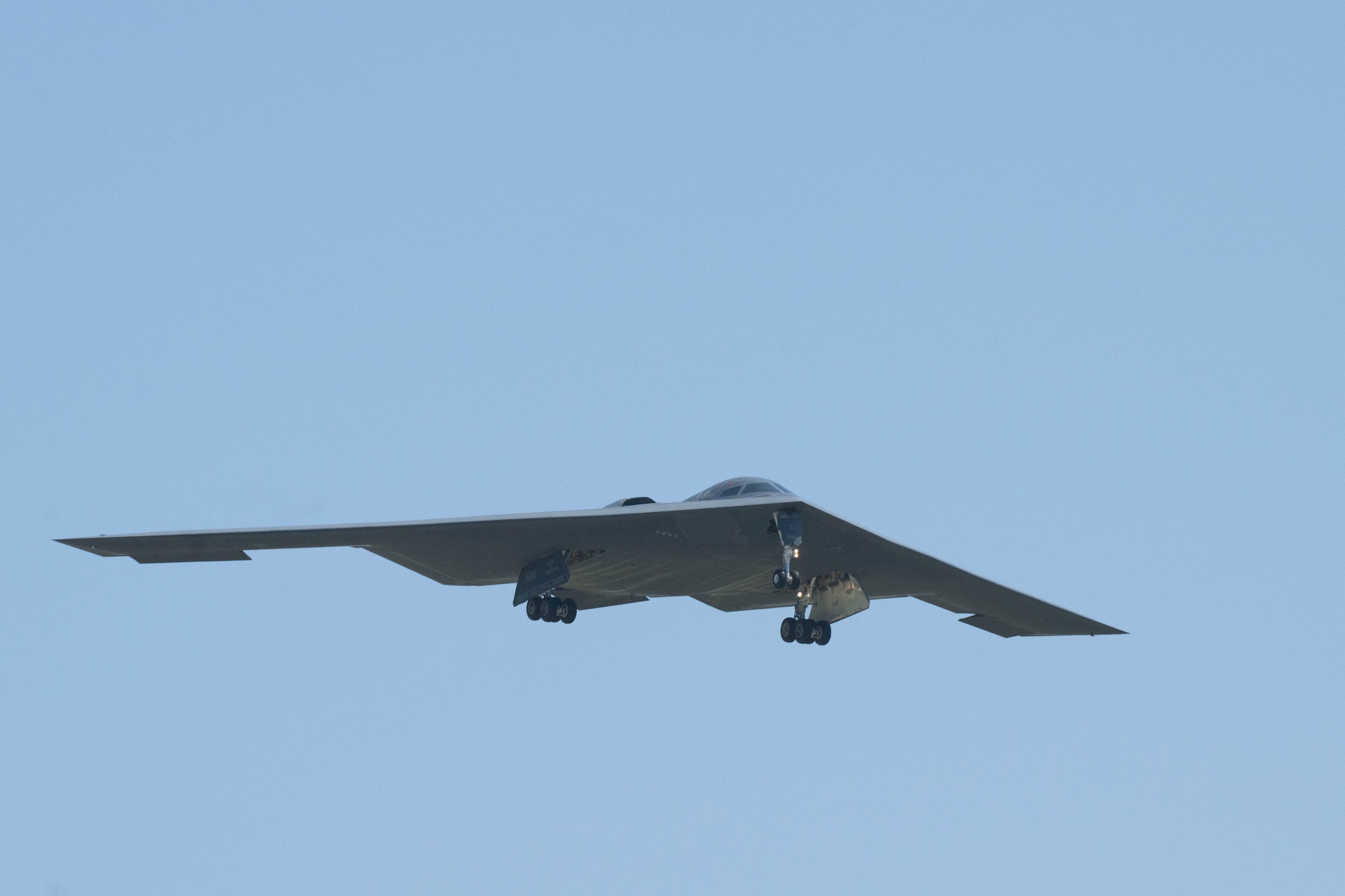 B-2 Spirit in flight, wheels out for landing, blue sky
