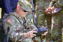 U.S. Army Staff Sgt. Eric Scuderi, a drone operator with 1st Battalion, 109th Infantry Regiment, 2nd Infantry Brigade Combat Team, 28th Infantry Division, remotely flies an unmanned aerial system during a demonstration at Fort Indiantown Gap, Pennsylvania, July 28, 2025. The Soldiers and representatives from Carnegie Mellon University’s Software Engineering Institute demonstrated Project Shrike, an AI-enabled system for rapid target recognition and fire adjustment, by integrating drones and artillery during live-fire training. (U.S. Army National Guard photo by Maj. Travis Mueller)