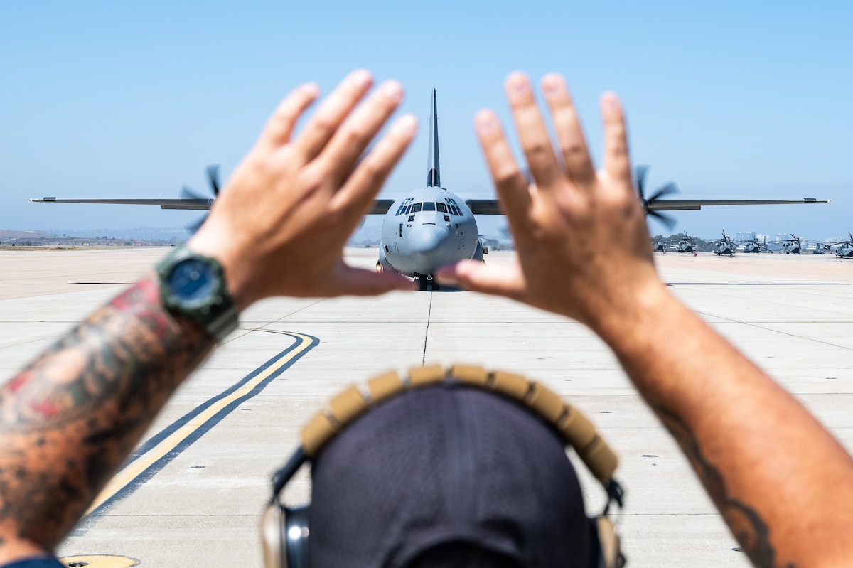 Airman stands in front of plane.