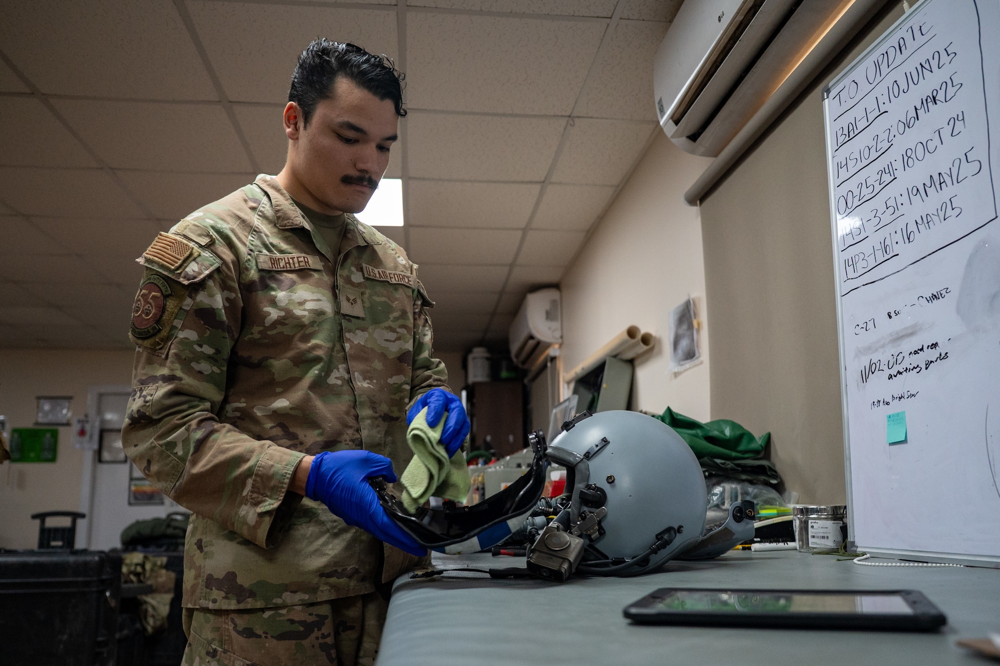 Airman wipes a helmet ensemble with a dust cloth