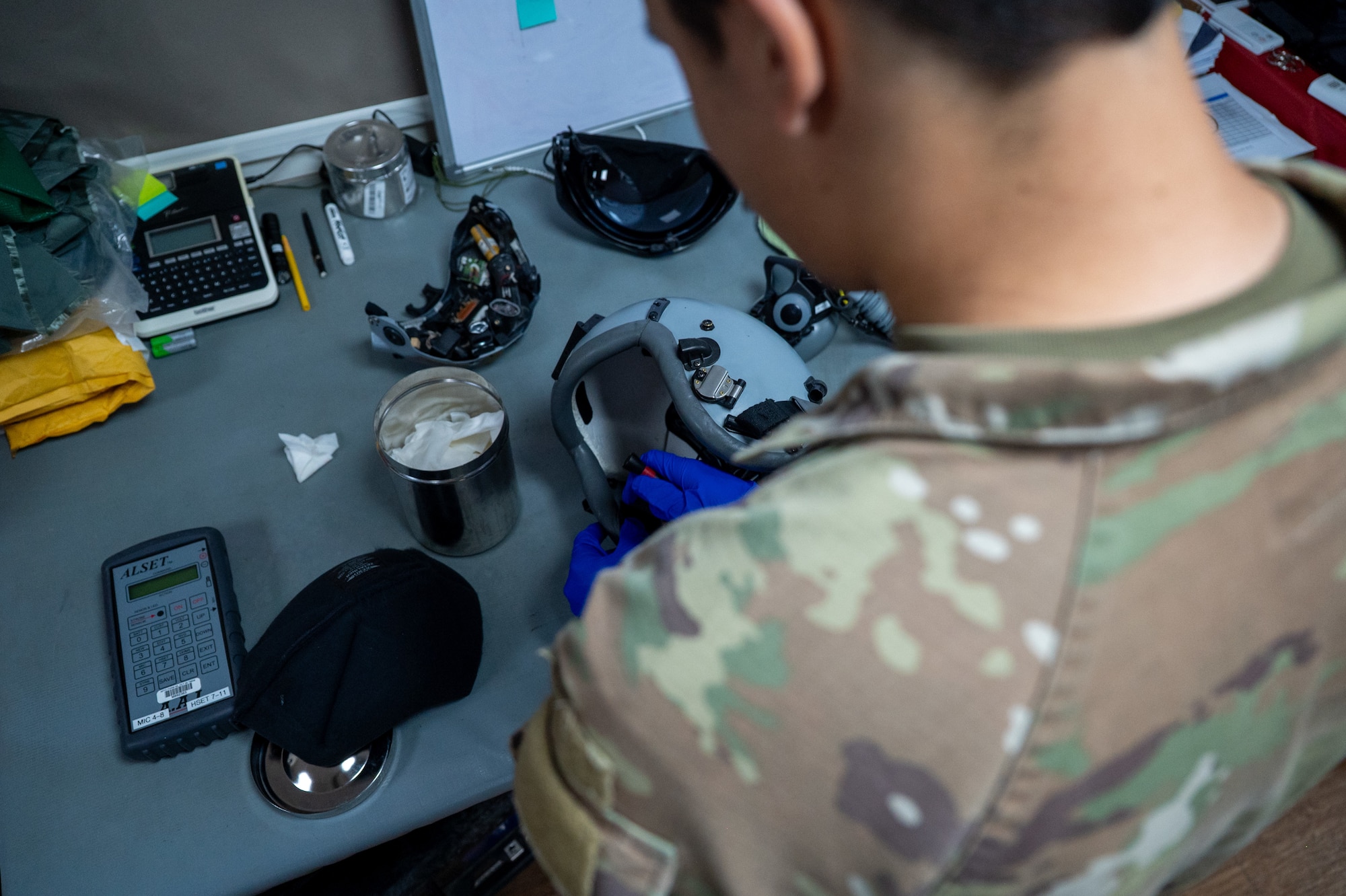 Airman visually inspects a helmet ensemble