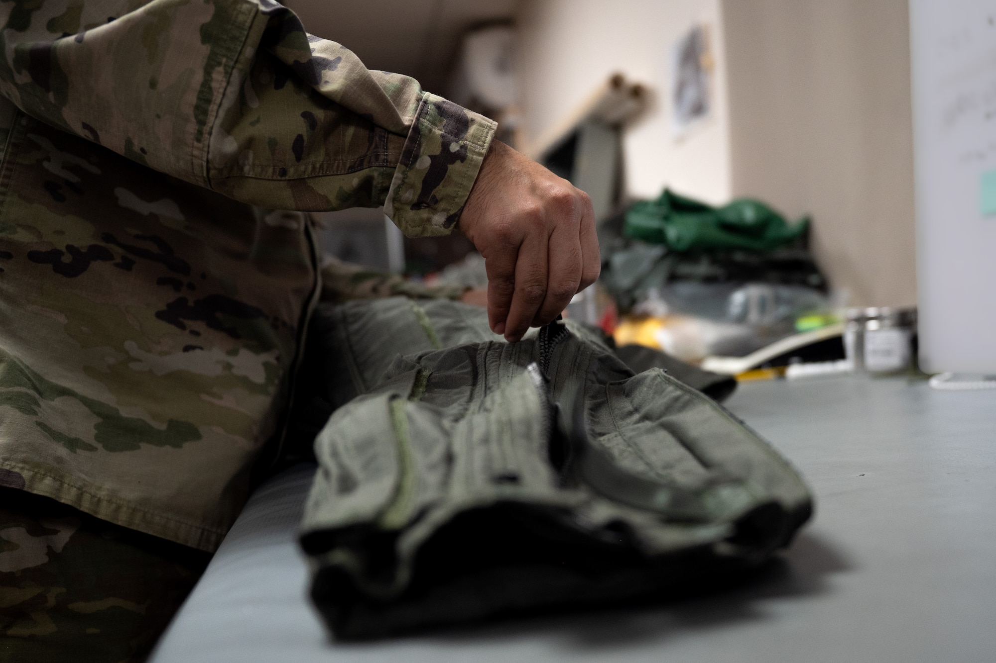 Airman closes a zipper on a pair of anti-g trousers