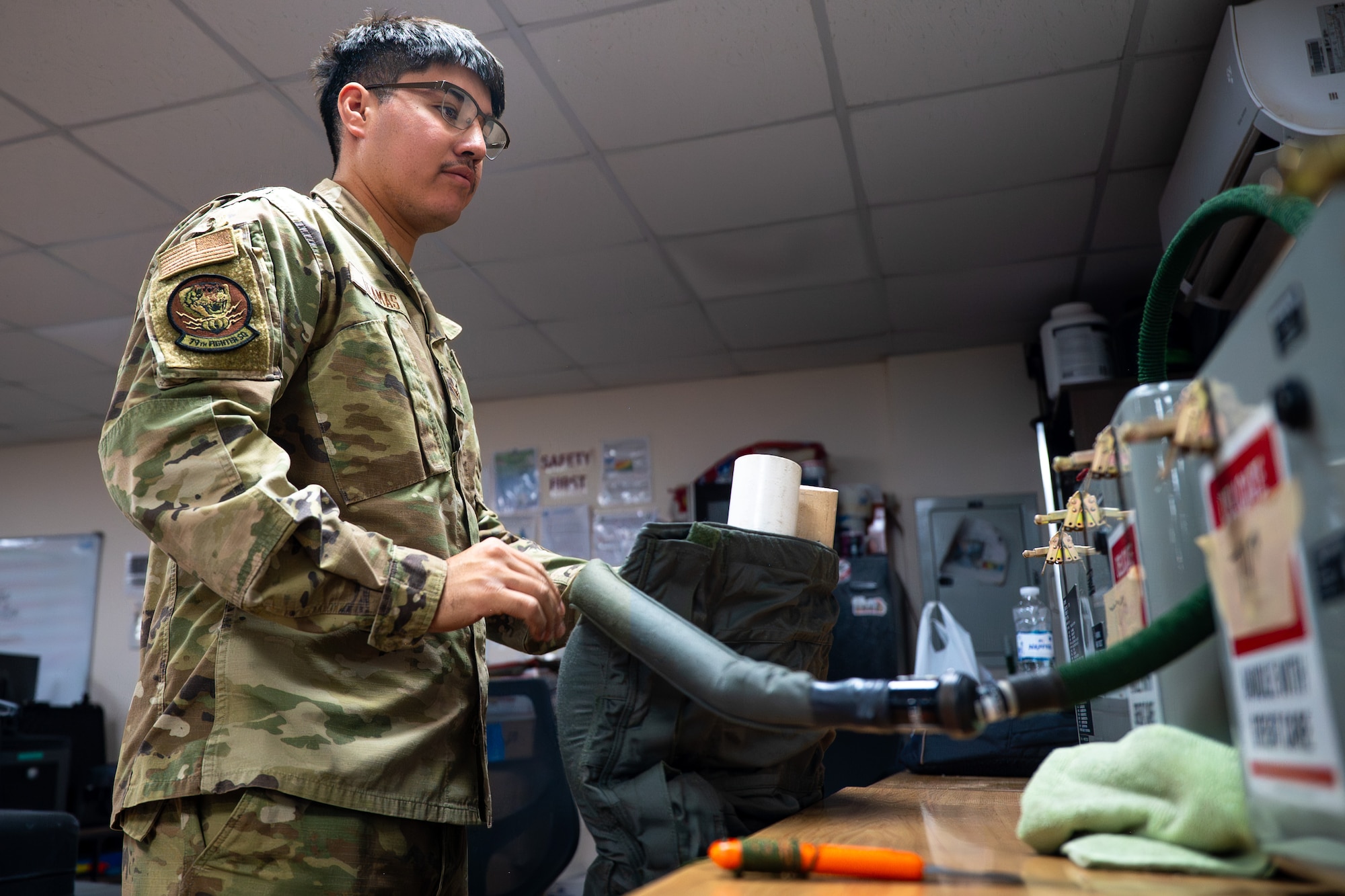 Airman connects a pair of anti-g trousers to a testing unit