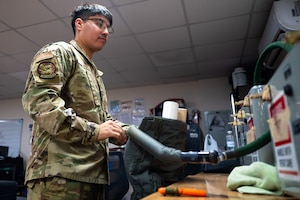 Airman connects a pair of anti-g trousers to a testing unit