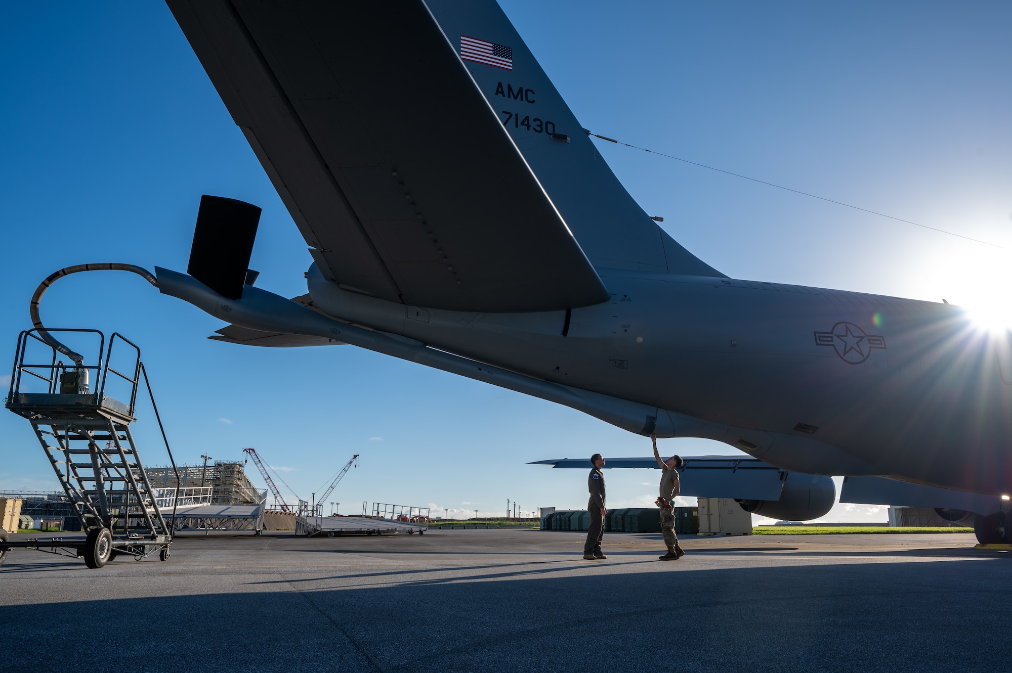 Two military member walk underneath a KC-135 Stratotanker aircraft for inspection