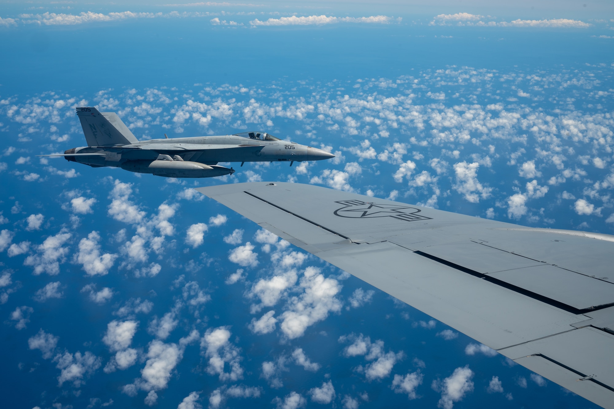 A F-18 aircraft flies next to the wing of a KC-135 aircraft
