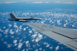 A F-18 aircraft flies next to the wing of a KC-135 aircraft