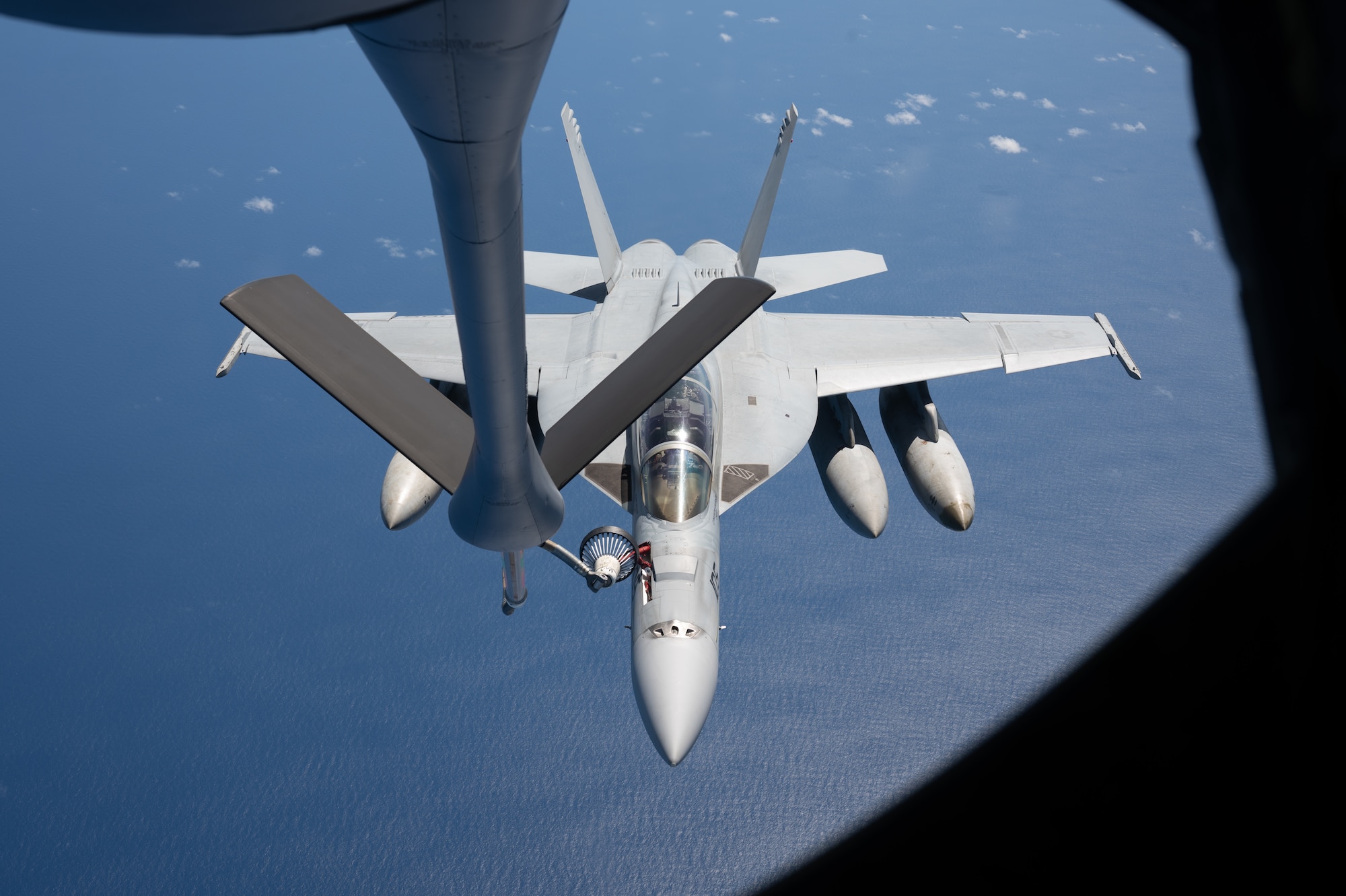 A F-18 aircraft flies behind a KC-135 to get refueled