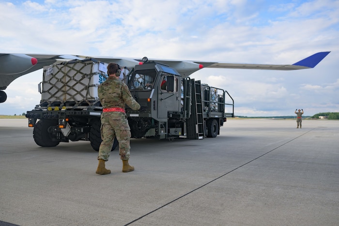 A U.S. Airman directs a loading truck away from the wing of a 747 aircraft.