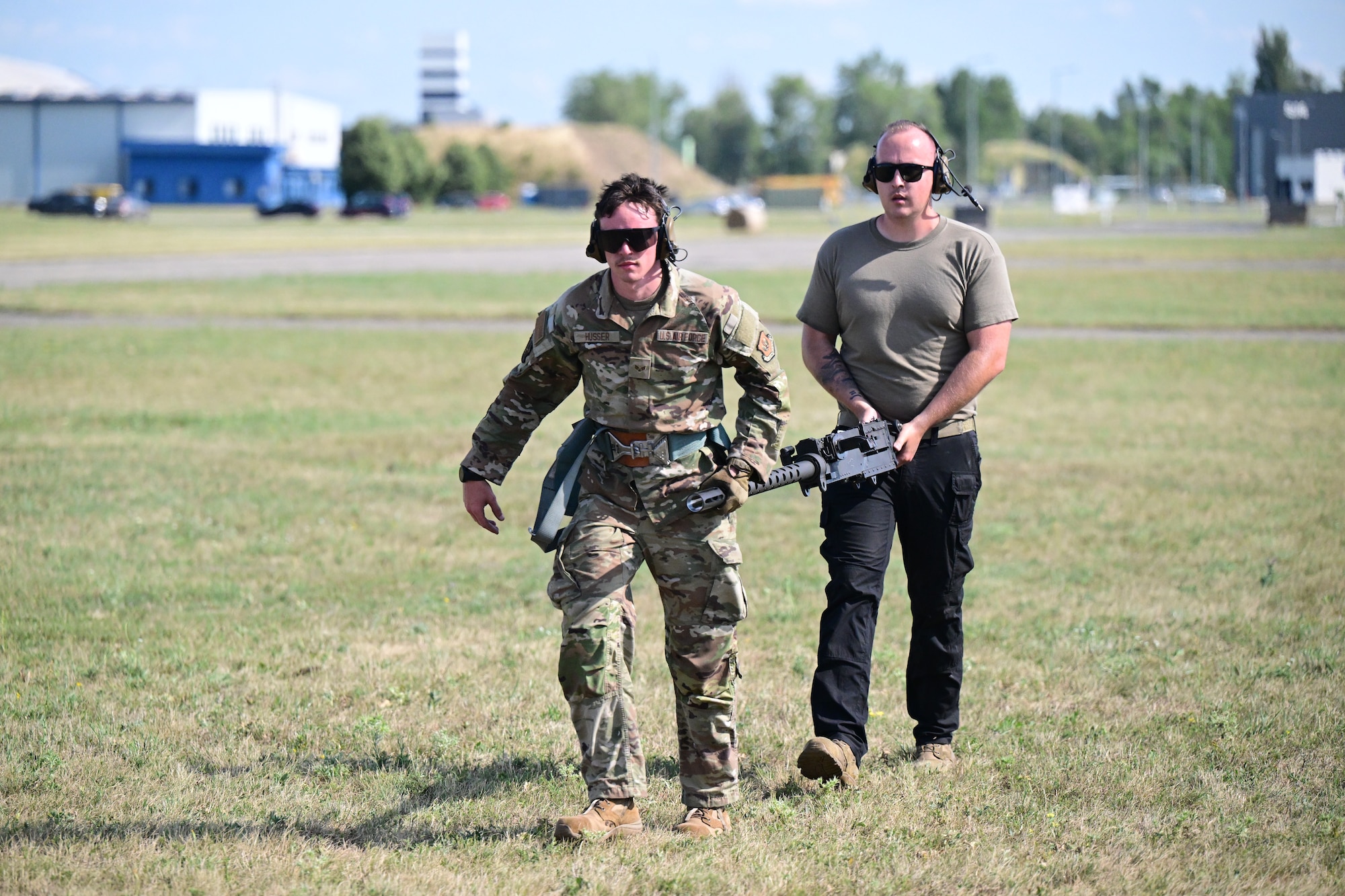 Weapons technicians carry a Gau-21 to the helicopter.