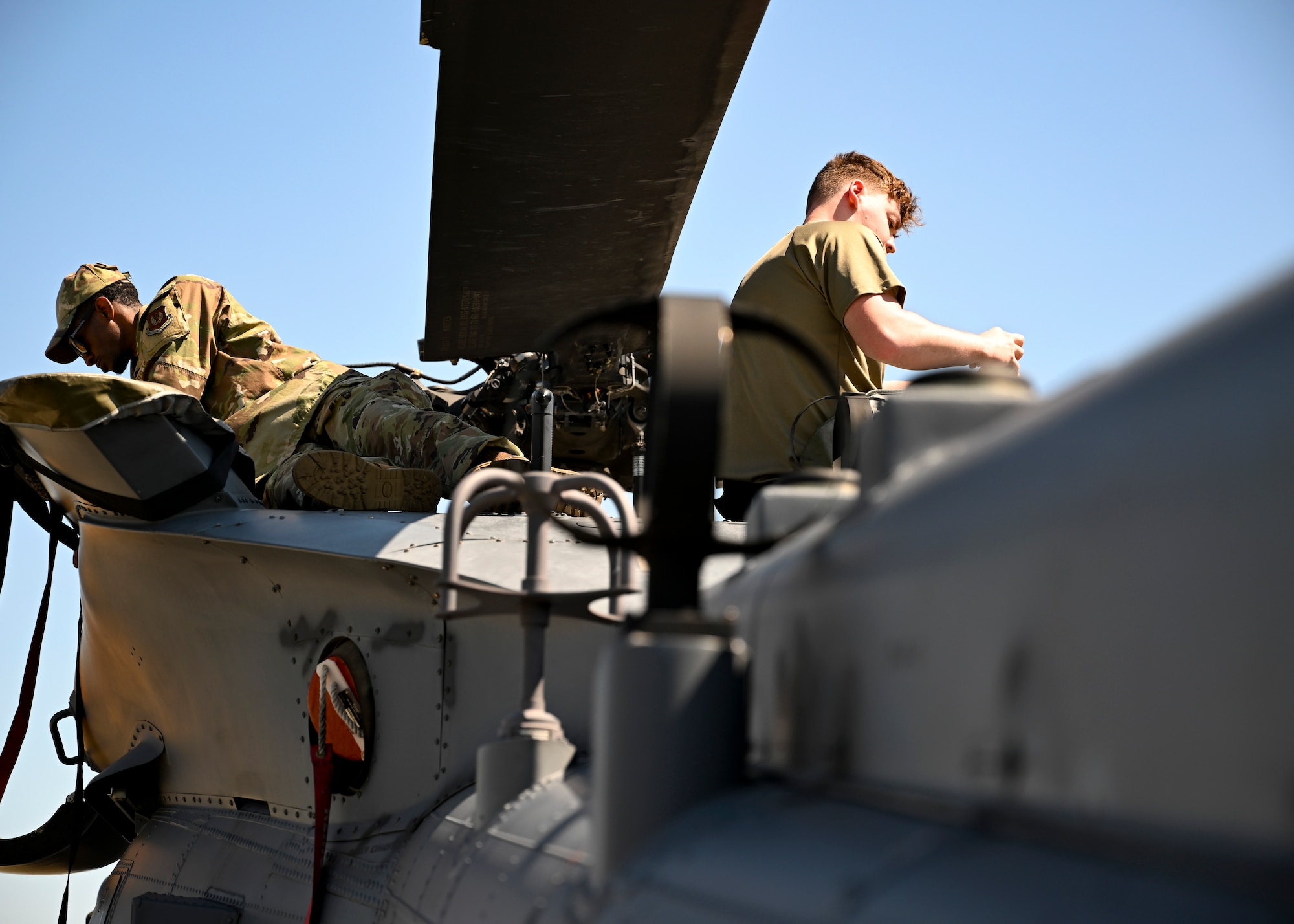 Maintainers installing engine exhaust covers onto the helicopter.