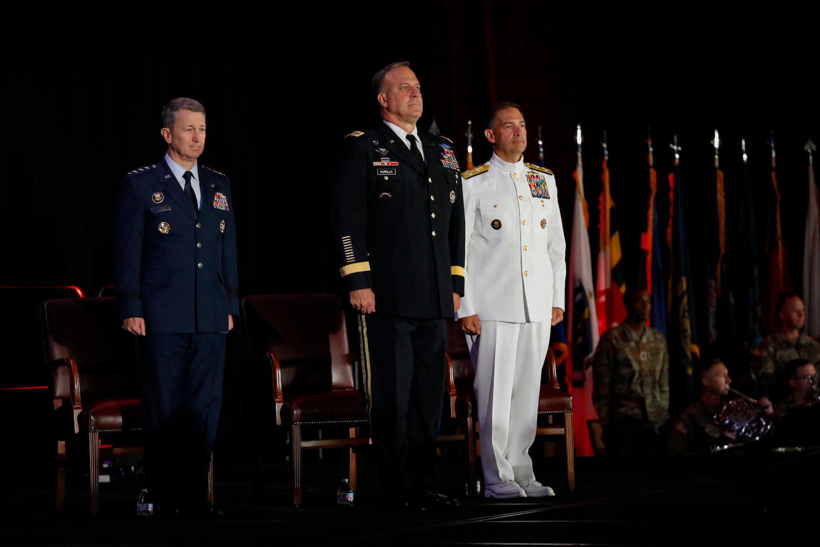 Chairman of the Joint Chiefs of Staff, U.S. Air Force Gen. Dan Caine, left, the outgoing commander of U.S. Central Command (USCENTCOM), U.S. Army Gen. Michael Erik Kurilla, center, and the incoming commander of USCENTCOM, U.S. Navy Adm. Brad Cooper, right, stand at attention at a change of command ceremony, 8 August 2025. Multiple Department of Defense officials attended the event as well as distinguished defense leaders from partner nations around the world. (U.S. Central Command Public Affairs photo by Tom Gagnier)